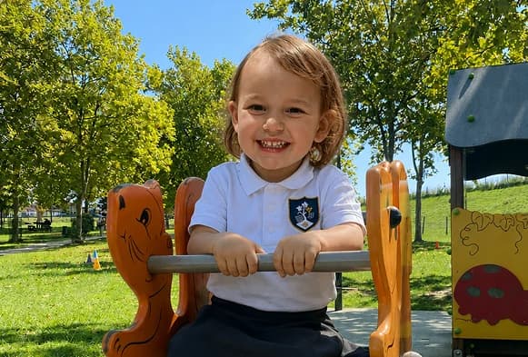 Un enfant de l'école Les Sarments souriant dans la cour de récréation